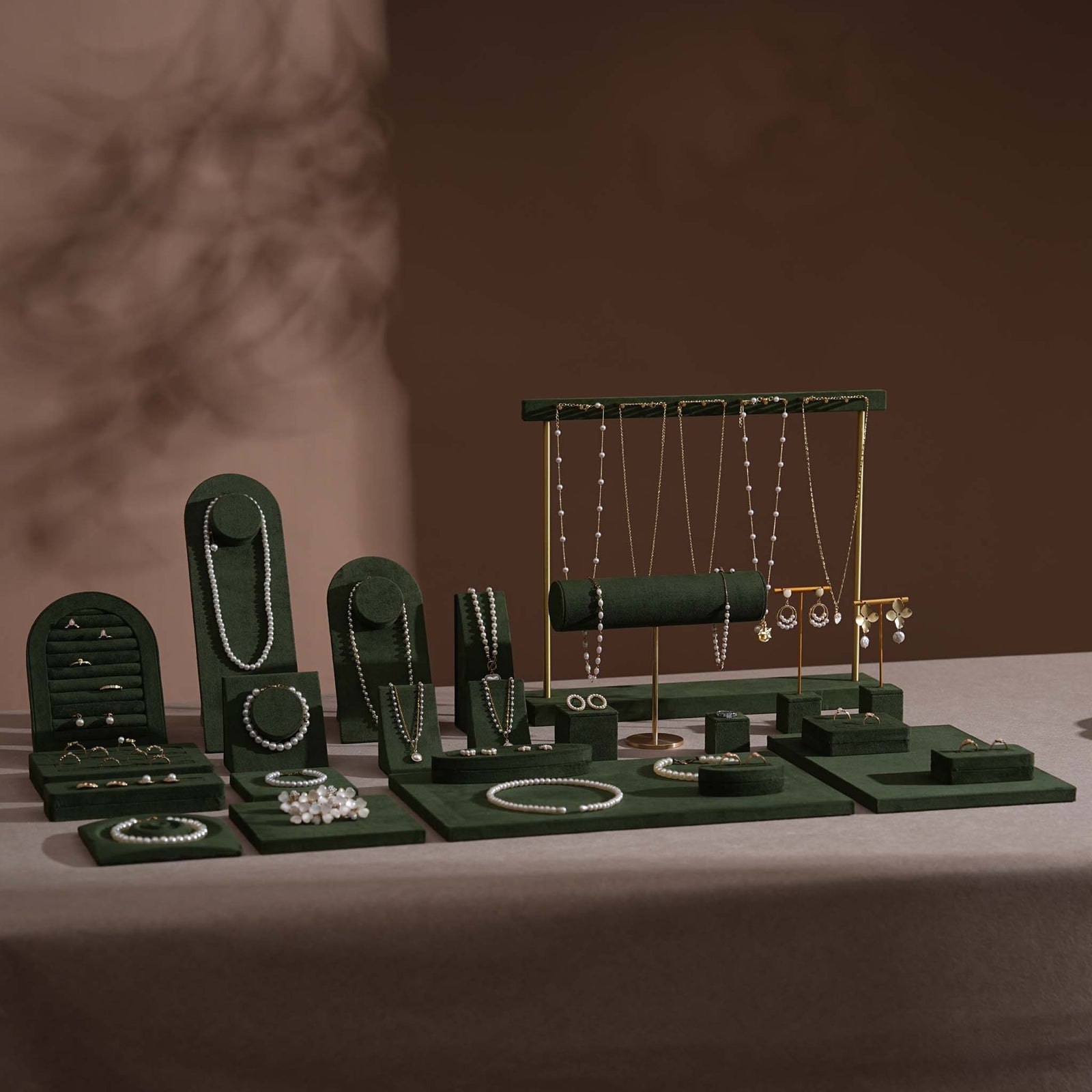 Forest green vegan suede trunk show jewelry display set with necklace busts, gold T-bar stands, bracelet roll, and ring trays styled with pearl and gold jewelry