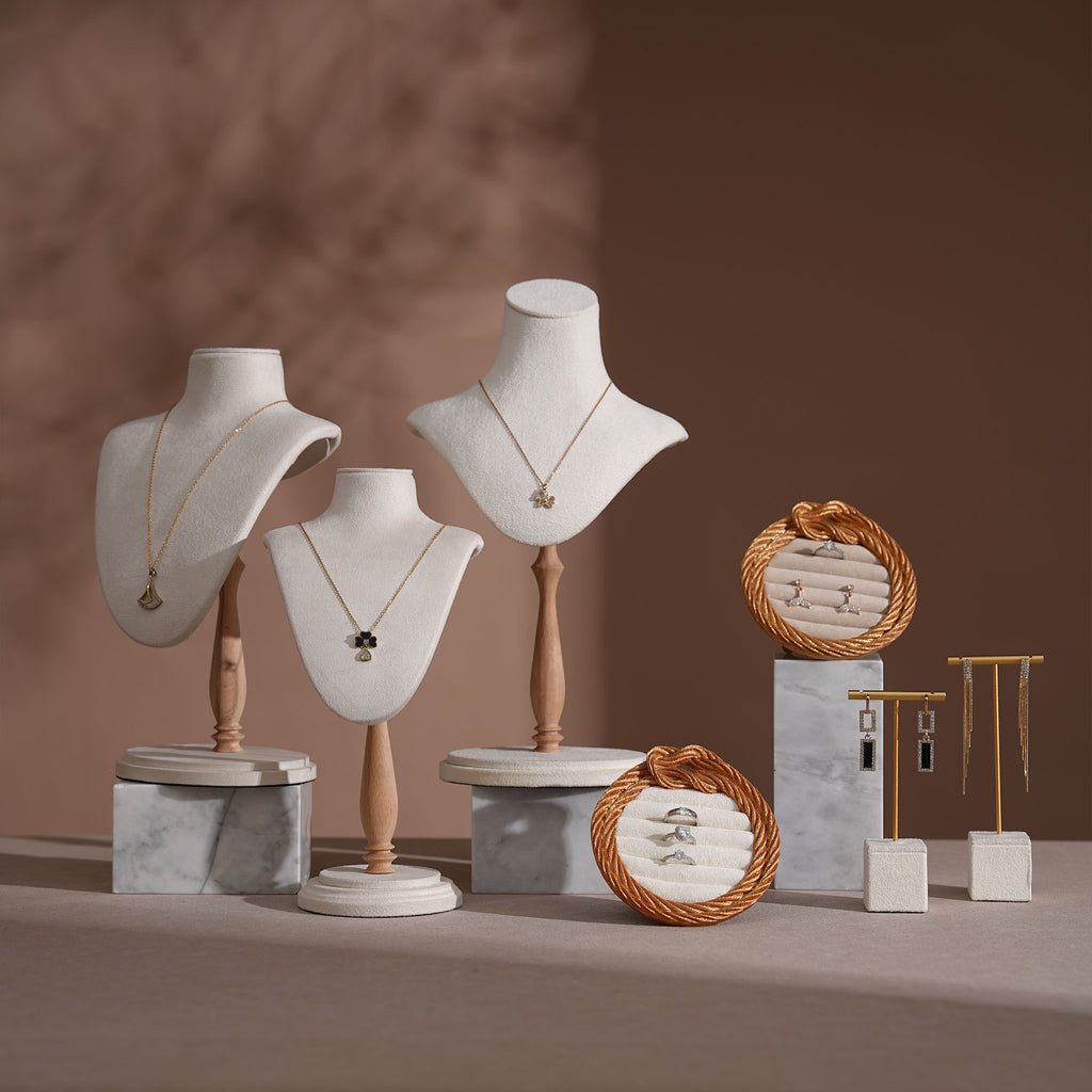 Jewelry display setup with mannequin heads, necklaces, and decorative items on a brown background