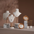 Jewelry display setup with mannequin heads, necklaces, and decorative items on a brown background