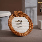Round jewelry holder with rope design containing three rings on a neutral background