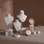 Jewelry display setup with necklaces on mannequin heads and earrings in woven holders against a brown background.