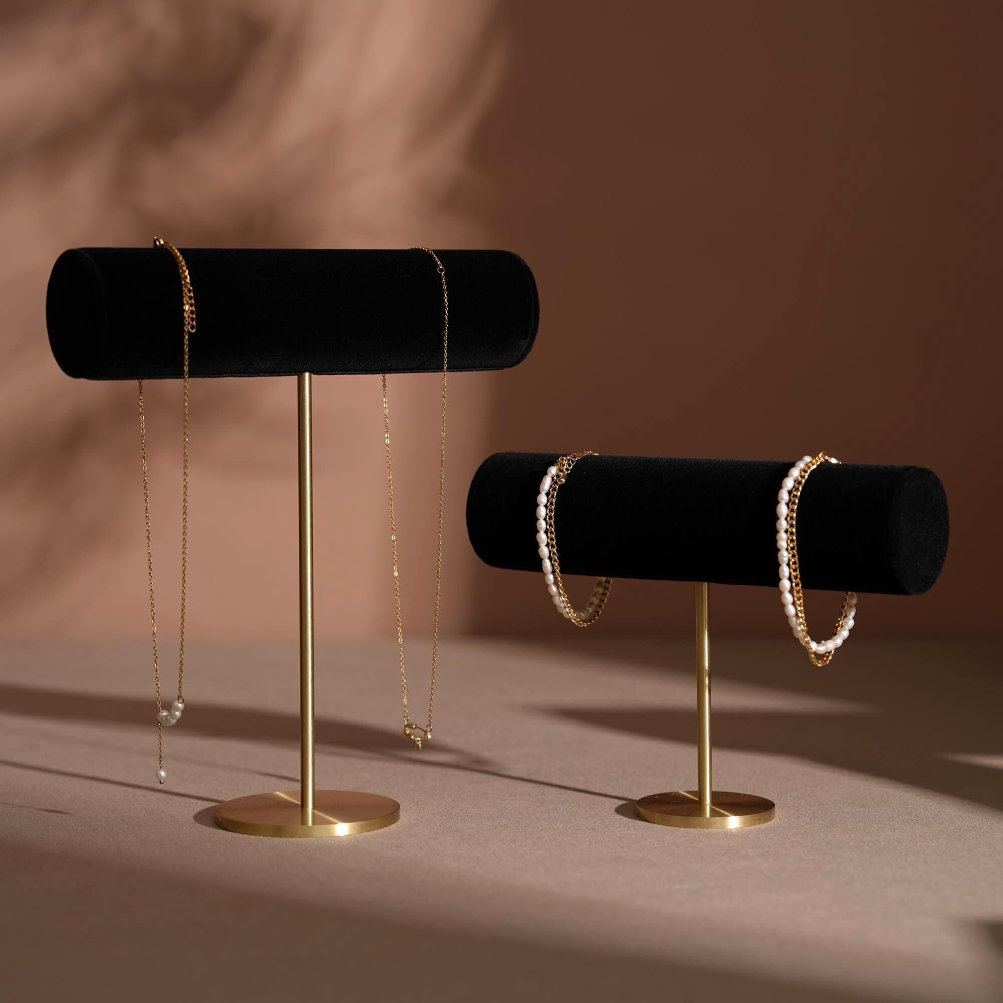 Jewelry display with gold necklace on brass stands against a brown background